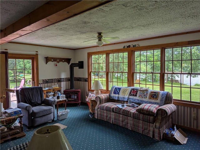 12941 Hillcrest Dr, Carlton, NY 14411 - living area featuring carpet floors, a wood stove, a ceiling fan, a textured ceiling, and a wainscoted wall