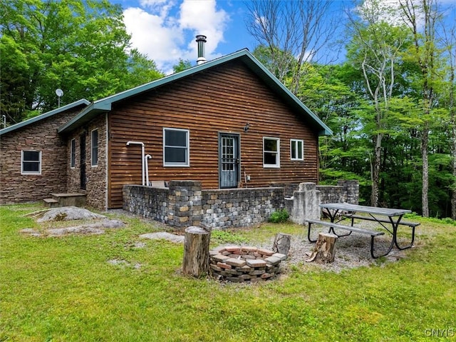 146 Mohawk Dr W, Webb, NY 13420 - rear view of house with stone siding, an outdoor fire pit, and a lawn