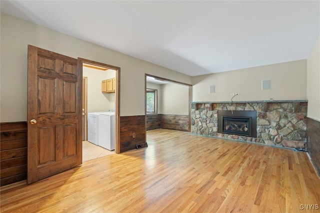 8013 Ginger Rd, Clay, NY 13090 - unfurnished living room featuring light wood finished floors, independent washer and dryer, a stone fireplace, and a wainscoted wall