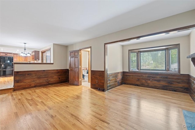 8013 Ginger Rd, Clay, NY 13090 - unfurnished living room with light wood-style floors, a chandelier, wainscoting, and wooden walls