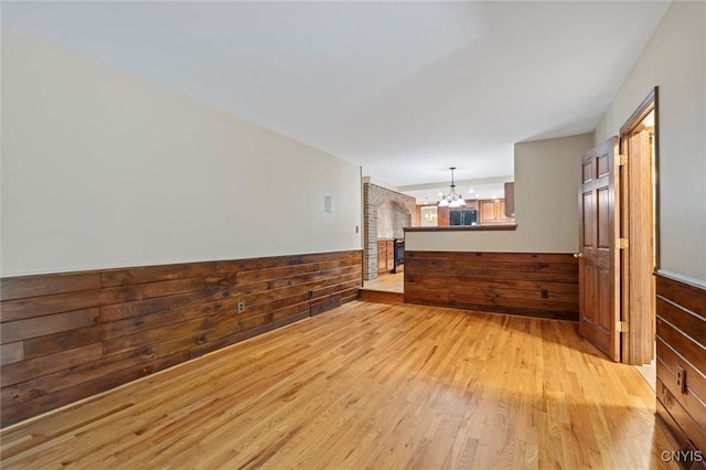 8013 Ginger Rd, Clay, NY 13090 - unfurnished living room featuring a chandelier, light wood-style flooring, wooden walls, and wainscoting
