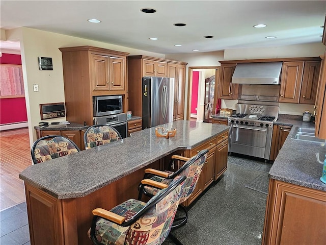 818 Larchmont Cir, Elmira, NY 14905 - kitchen featuring stainless steel appliances, wall chimney exhaust hood, a breakfast bar area, a kitchen island, and a baseboard radiator