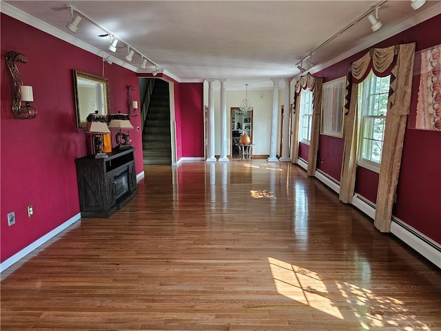 818 Larchmont Cir, Elmira, NY 14905 - unfurnished living room featuring rail lighting, ornate columns, ornamental molding, wood finished floors, and stairway