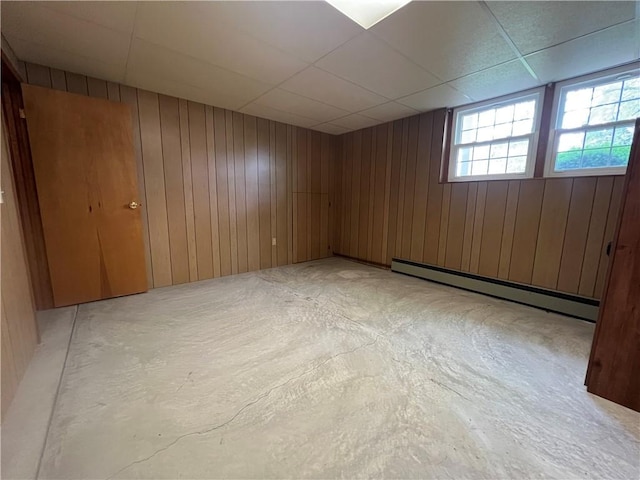 6 Meadowbrook Ter, North Dansville, NY 14437 - unfurnished room featuring a baseboard heating unit, wooden walls, a paneled ceiling, and concrete flooring