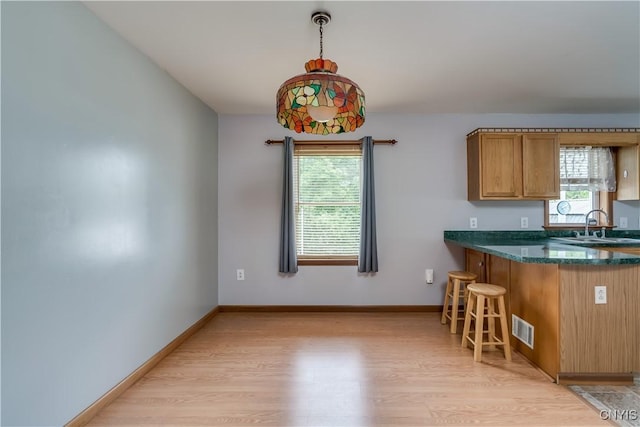 60 Van Buren St, Antwerp, NY 13608 - kitchen featuring light wood-type flooring, a breakfast bar area, dark stone countertops, brown cabinetry, and a peninsula