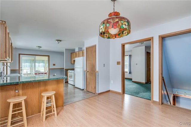 60 Van Buren St, Antwerp, NY 13608 - kitchen with white appliances, light wood-style flooring, a peninsula, a kitchen breakfast bar, and brown cabinets
