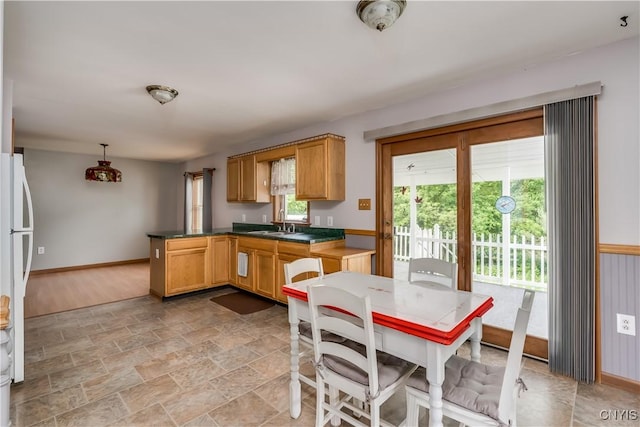 60 Van Buren St, Antwerp, NY 13608 - kitchen with a peninsula, freestanding refrigerator, dark countertops, light stone finish floors, and decorative light fixtures