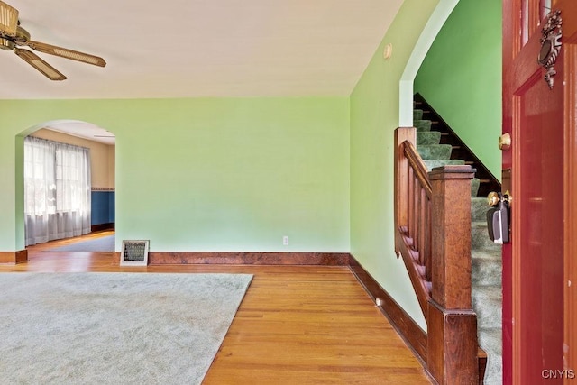 217 Mackay Ave, Camillus, NY 13219 - unfurnished living room featuring ceiling fan, wood finished floors, arched walkways, and stairs