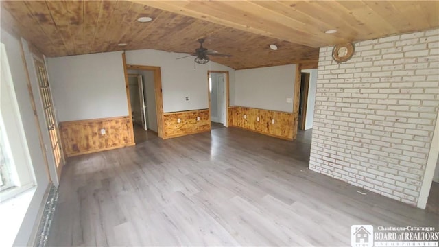 4010 Main St, Scio, NY 14880 - unfurnished living room featuring a ceiling fan, wainscoting, wood finished floors, lofted ceiling, and wood walls
