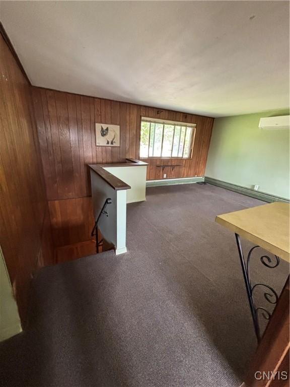6473 Wembridge Dr, Dewitt, NY 13057 - unfurnished living room with wooden walls, dark carpet, a baseboard heating unit, and a wall unit AC