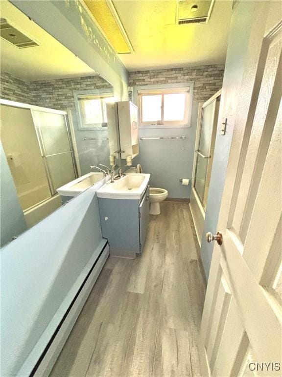6473 Wembridge Dr, Dewitt, NY 13057 - bathroom featuring vanity, wood finished floors, bath / shower combo with glass door, and baseboard heating