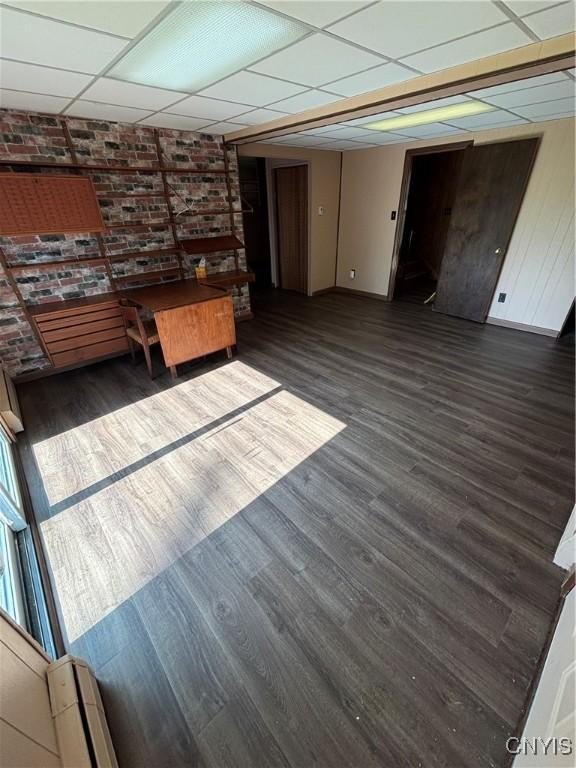 6473 Wembridge Dr, Dewitt, NY 13057 - unfurnished living room with a drop ceiling, wood finished floors, and brick wall