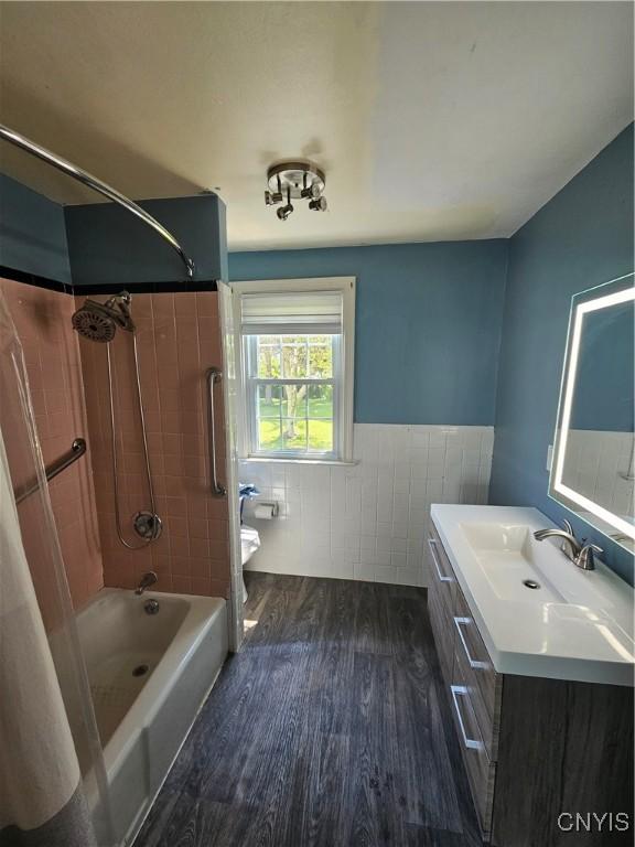 203 Windemere Rd, Geddes, NY 13219 - bathroom featuring wood finished floors, tile walls, vanity, shower / bathtub combination, and a wainscoted wall