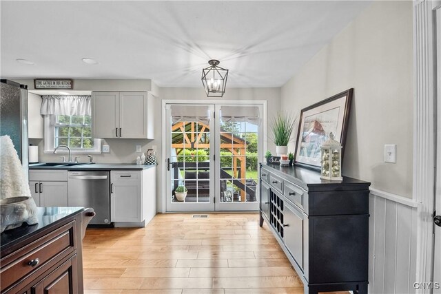 150 E Hawthorne Way, Sullivan, NY 13037 - kitchen with dishwasher, light wood-type flooring, dark countertops, a chandelier, and wainscoting
