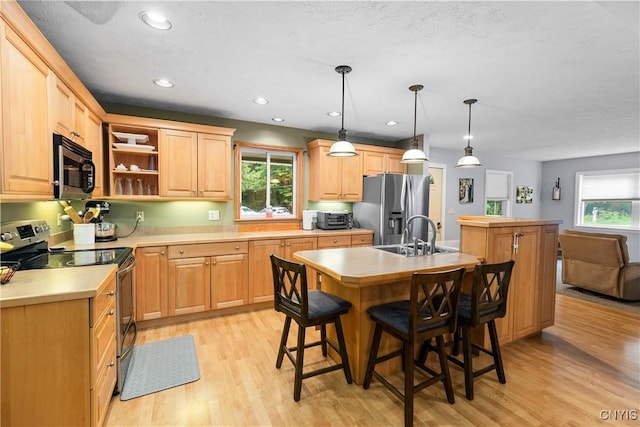 10327 Wolcott Hill Rd, Camden, NY 13316 - kitchen featuring stainless steel appliances, an island with sink, light wood finished floors, light brown cabinetry, and light countertops