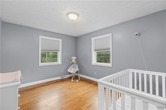 10327 Wolcott Hill Rd, Camden, NY 13316 - unfurnished bedroom featuring light wood-style floors, a crib, and a textured ceiling