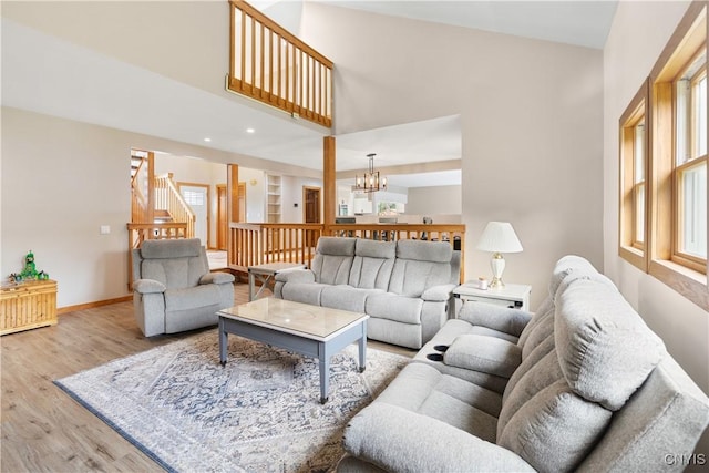 4925 Bentbrook Dr, Manlius, NY 13104 - living room featuring a chandelier, a towering ceiling, wood finished floors, plenty of natural light, and stairs