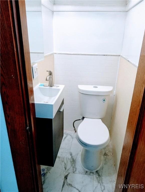 2436 Cleveland Ave, Niagara Falls, NY 14305 - half bath featuring vanity, marble look tiles, and a wainscoted wall