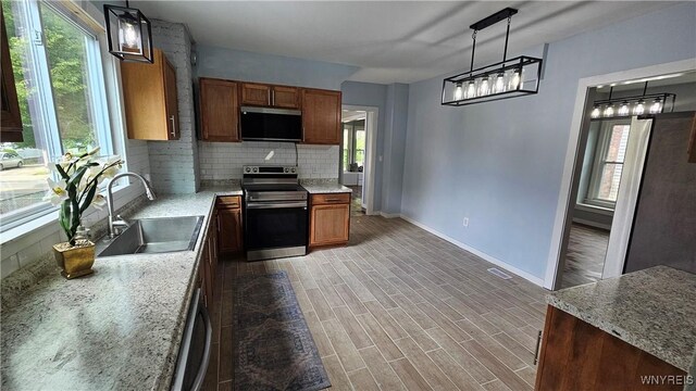 726 S Main St, Shelby, NY 14103 - kitchen featuring stainless steel appliances, tasteful backsplash, brown cabinetry, and decorative light fixtures