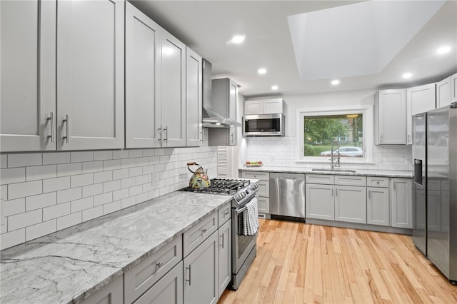 100 Carverdale Dr, Brighton, NY 14618 - kitchen featuring stainless steel appliances, wall chimney exhaust hood, light stone countertops, light wood finished floors, and backsplash
