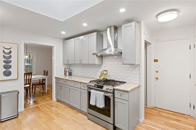 100 Carverdale Dr, Brighton, NY 14618 - kitchen with stainless steel gas stove, wall chimney exhaust hood, gray cabinetry, light wood-type flooring, and tasteful backsplash