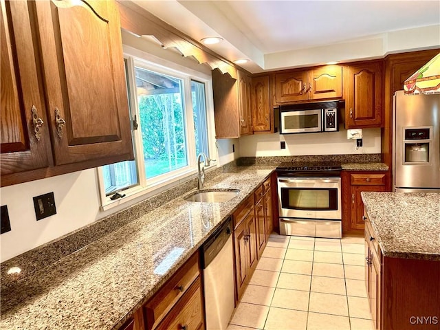 1000 Sherman Dr, Utica, NY 13501 - kitchen featuring appliances with stainless steel finishes, dark stone counters, light tile patterned floors, and brown cabinets