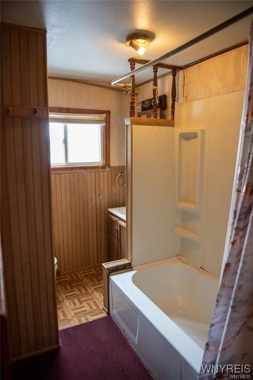 150 Weiss St, Buffalo, NY 14206 - bathroom featuring wood walls, a wainscoted wall, and shower / bathtub combination with curtain