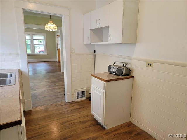 2255 Ontario Ave, Niagara Falls, NY 14305 - kitchen with tile walls, dark wood finished floors, a wainscoted wall, white cabinetry, and hanging light fixtures