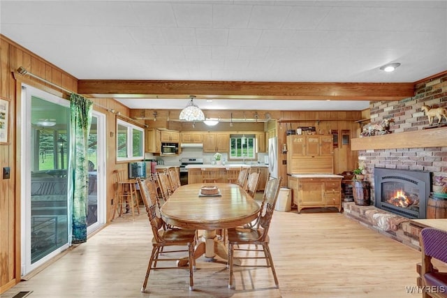 6557 Boberg Rd, Ashford, NY 14171 - dining space featuring light wood-type flooring, beam ceiling, healthy amount of natural light, wood walls, and a brick fireplace