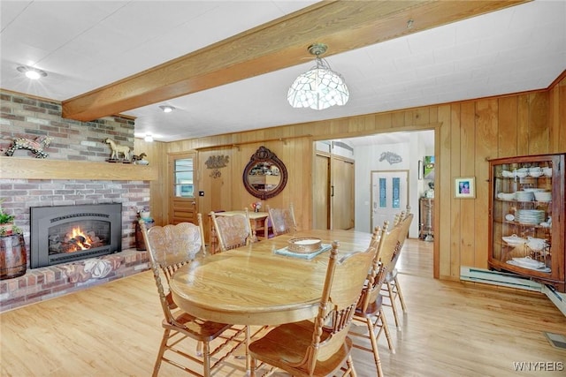 6557 Boberg Rd, Ashford, NY 14171 - dining space featuring wooden walls, light wood-style floors, beam ceiling, and a brick fireplace