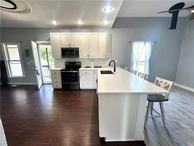 14918 Lakeshore Rd, Carlton, NY 14477 - kitchen featuring electric range oven, stainless steel microwave, a peninsula, a breakfast bar, and light countertops