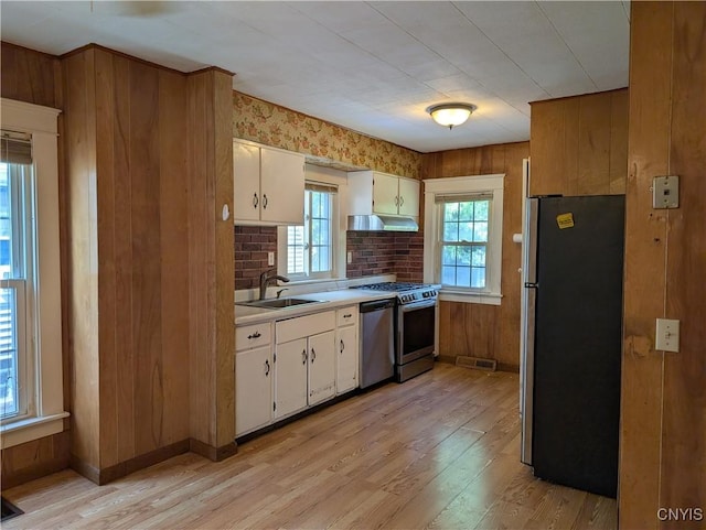 305 S Midler Ave, Syracuse, NY 13206 - kitchen with stainless steel appliances, light wood-style flooring, light countertops, white cabinetry, and wood walls