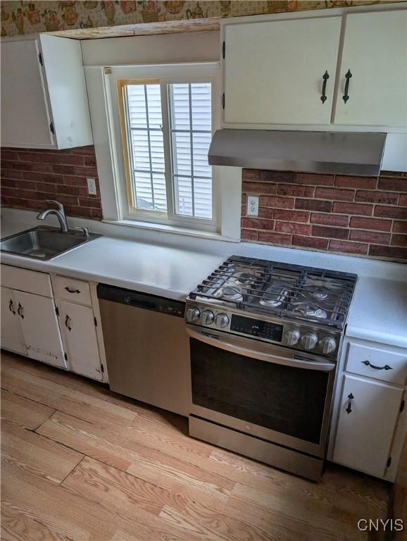 305 S Midler Ave, Syracuse, NY 13206 - kitchen with stainless steel appliances, white cabinets, light countertops, tasteful backsplash, and light wood-style flooring