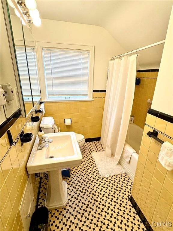 308 Haddonfield Dr, Dewitt, NY 13214 - bathroom featuring tile walls, shower / tub combo with curtain, healthy amount of natural light, wainscoting, and vaulted ceiling