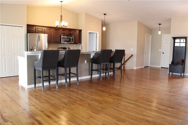4745 Lynnville, Clay, NY 13041 - kitchen featuring appliances with stainless steel finishes, a breakfast bar, light wood-style floors, vaulted ceiling, and pendant lighting