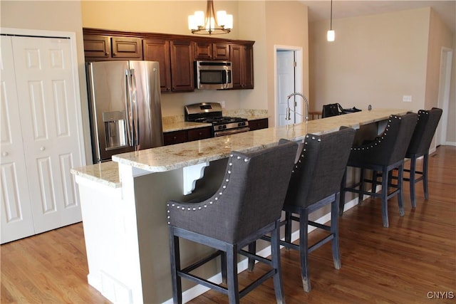 4745 Lynnville, Clay, NY 13041 - kitchen featuring stainless steel appliances, wood finished floors, decorative light fixtures, and a kitchen breakfast bar