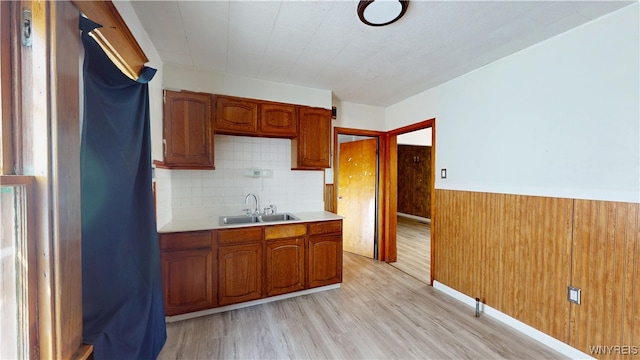 133 Freund St, Buffalo, NY 14215 - kitchen with brown cabinets, light countertops, light wood-style flooring, a wainscoted wall, and backsplash