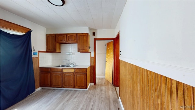 133 Freund St, Buffalo, NY 14215 - kitchen featuring brown cabinets, light wood finished floors, light countertops, wainscoting, and decorative backsplash