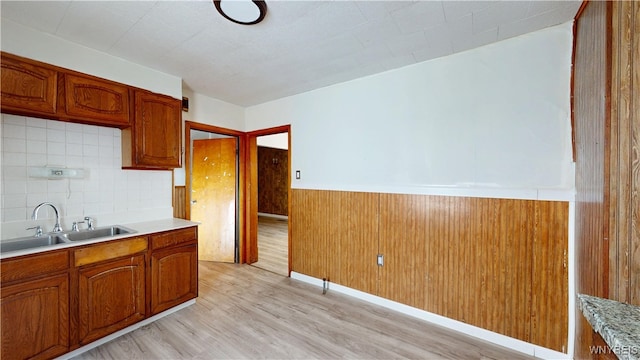133 Freund St, Buffalo, NY 14215 - kitchen featuring light wood-type flooring, light countertops, brown cabinets, wainscoting, and backsplash