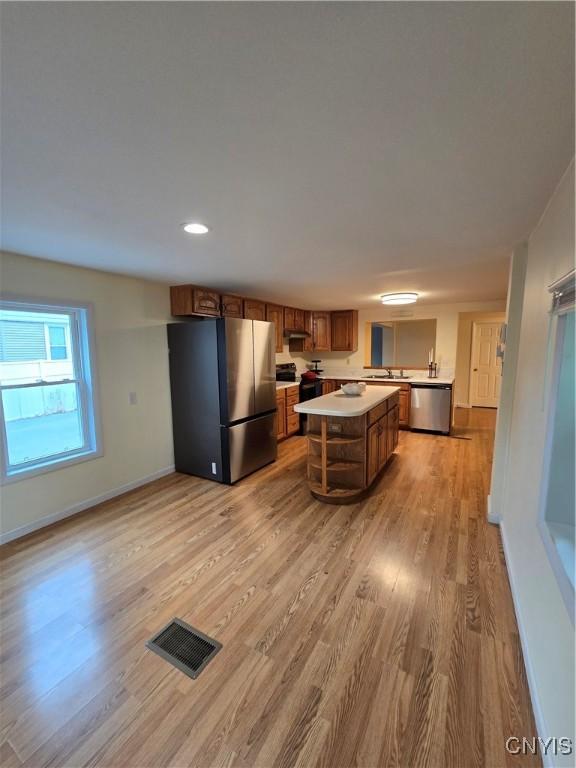 259 Flower Ave W, Watertown-City, NY 13601 - kitchen with appliances with stainless steel finishes, light countertops, light wood-type flooring, brown cabinetry, and a kitchen island