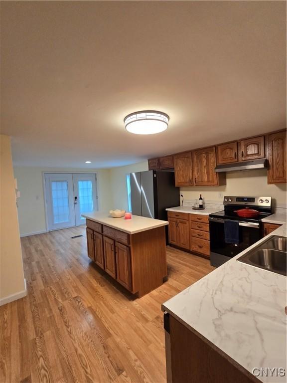 259 Flower Ave W, Watertown-City, NY 13601 - kitchen with electric range, freestanding refrigerator, under cabinet range hood, light wood-type flooring, and a kitchen island