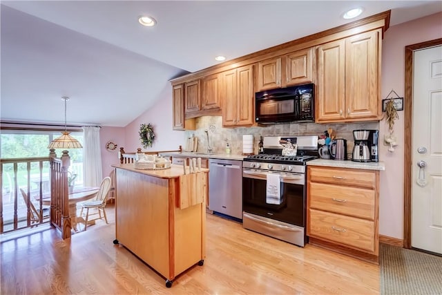 921 Wayneport Rd, Macedon, NY 14502 - kitchen featuring stainless steel appliances, vaulted ceiling, light wood finished floors, light countertops, and a kitchen island