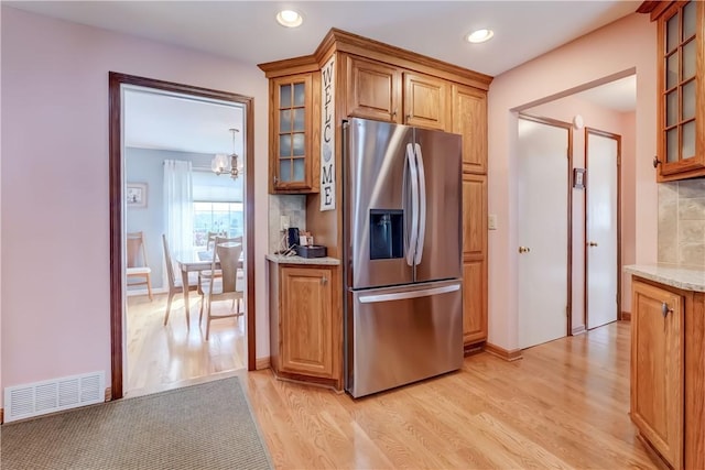 921 Wayneport Rd, Macedon, NY 14502 - kitchen with stainless steel fridge with ice dispenser, light wood finished floors, glass insert cabinets, a chandelier, and decorative backsplash