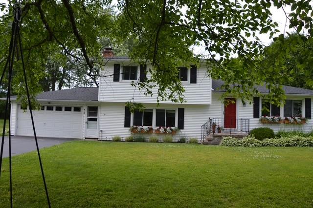 57 Timberline Dr, Penfield, NY 14526 - split level home featuring a garage, a front lawn, concrete driveway, and a chimney