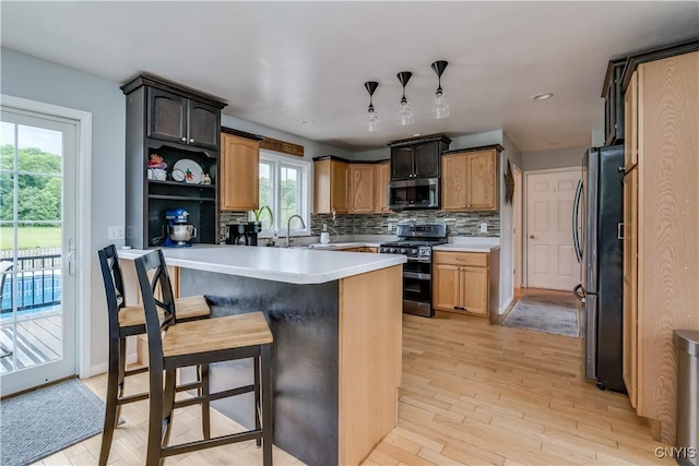 33039 County Route 22, Antwerp, NY 13691 - kitchen with stainless steel appliances, tasteful backsplash, light wood-style flooring, a kitchen breakfast bar, and light countertops