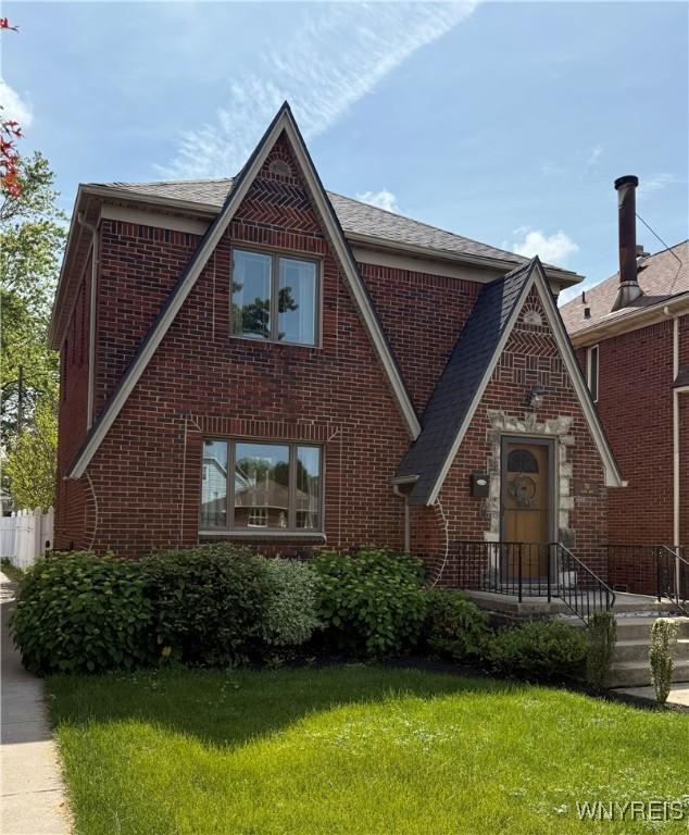711 Colvin Blvd, Tonawanda-Town, NY 14217 - tudor home with brick siding, a front lawn, and a shingled roof