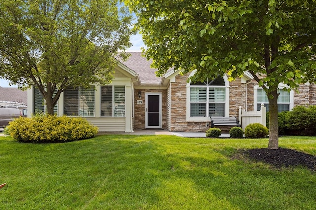 189 Maryview Dr, Penfield, NY 14580 - view of property hidden behind natural elements with stone siding, a front yard, and roof with shingles
