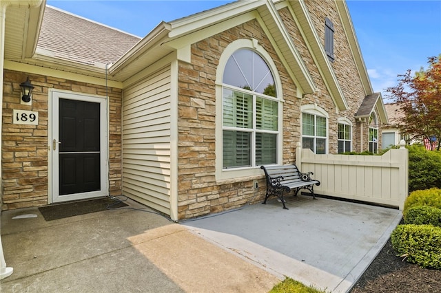 189 Maryview Dr, Penfield, NY 14580 - property entrance featuring stone siding, a shingled roof, and a patio