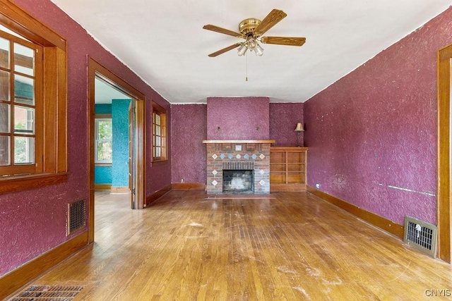 218-20 Avery Ave, Syracuse, NY 13204 - unfurnished living room with wood finished floors, a fireplace, ceiling fan, and a textured wall