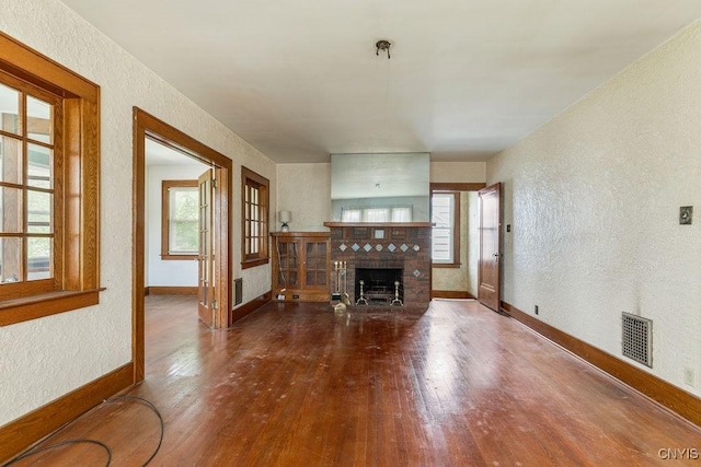 218-20 Avery Ave, Syracuse, NY 13204 - unfurnished living room featuring a textured wall, wood finished floors, plenty of natural light, and a fireplace